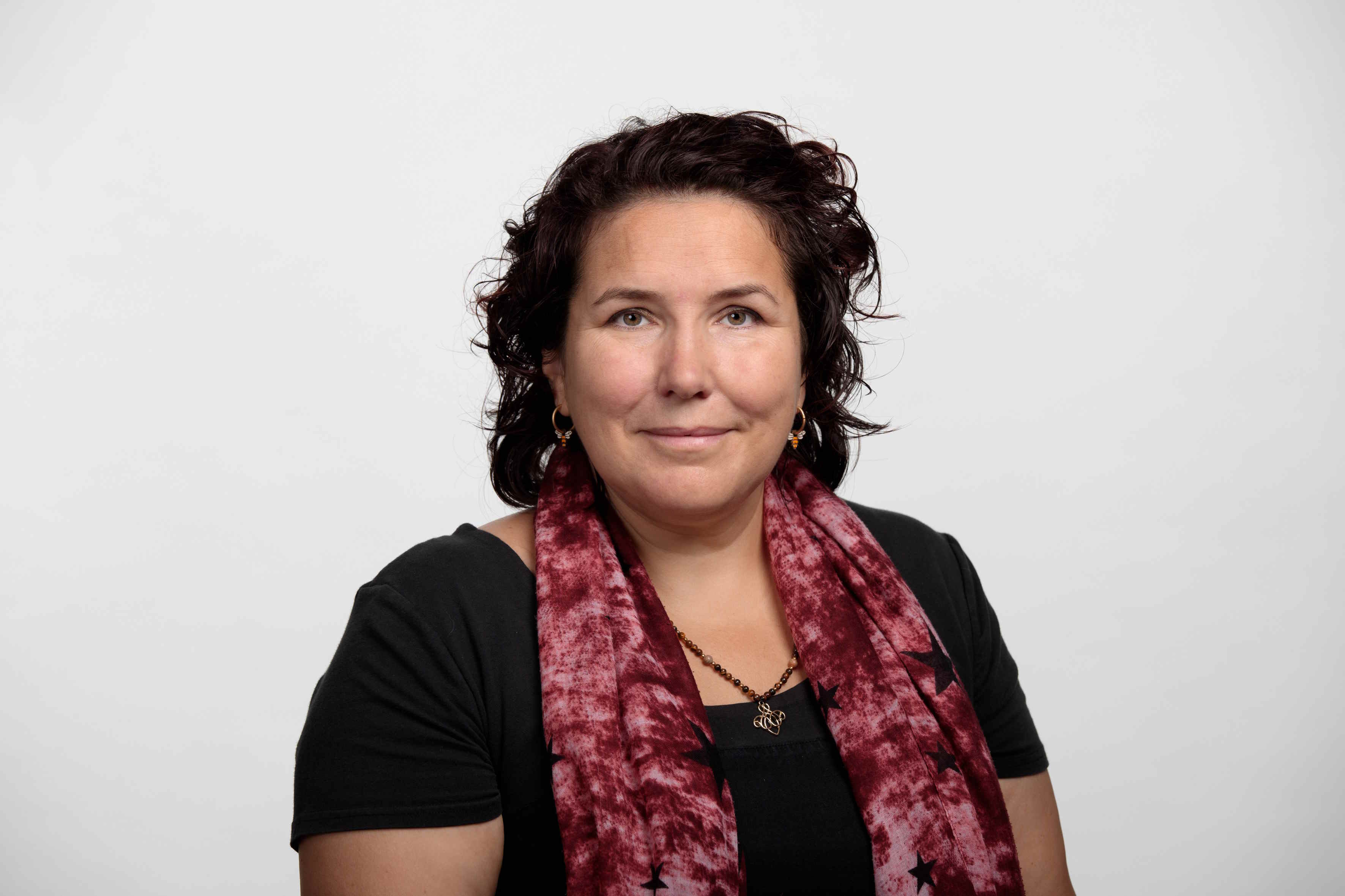Portraitbild einer weissen Frau mit dunklen lockigen Haaren und einem roten Schal